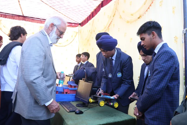 Students demonstrating a robotic vehicle beside a laptop